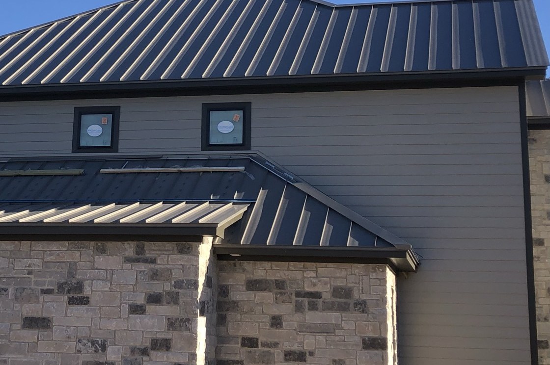 Seamless gutter run and fascia along a finished eave, stone and siding building