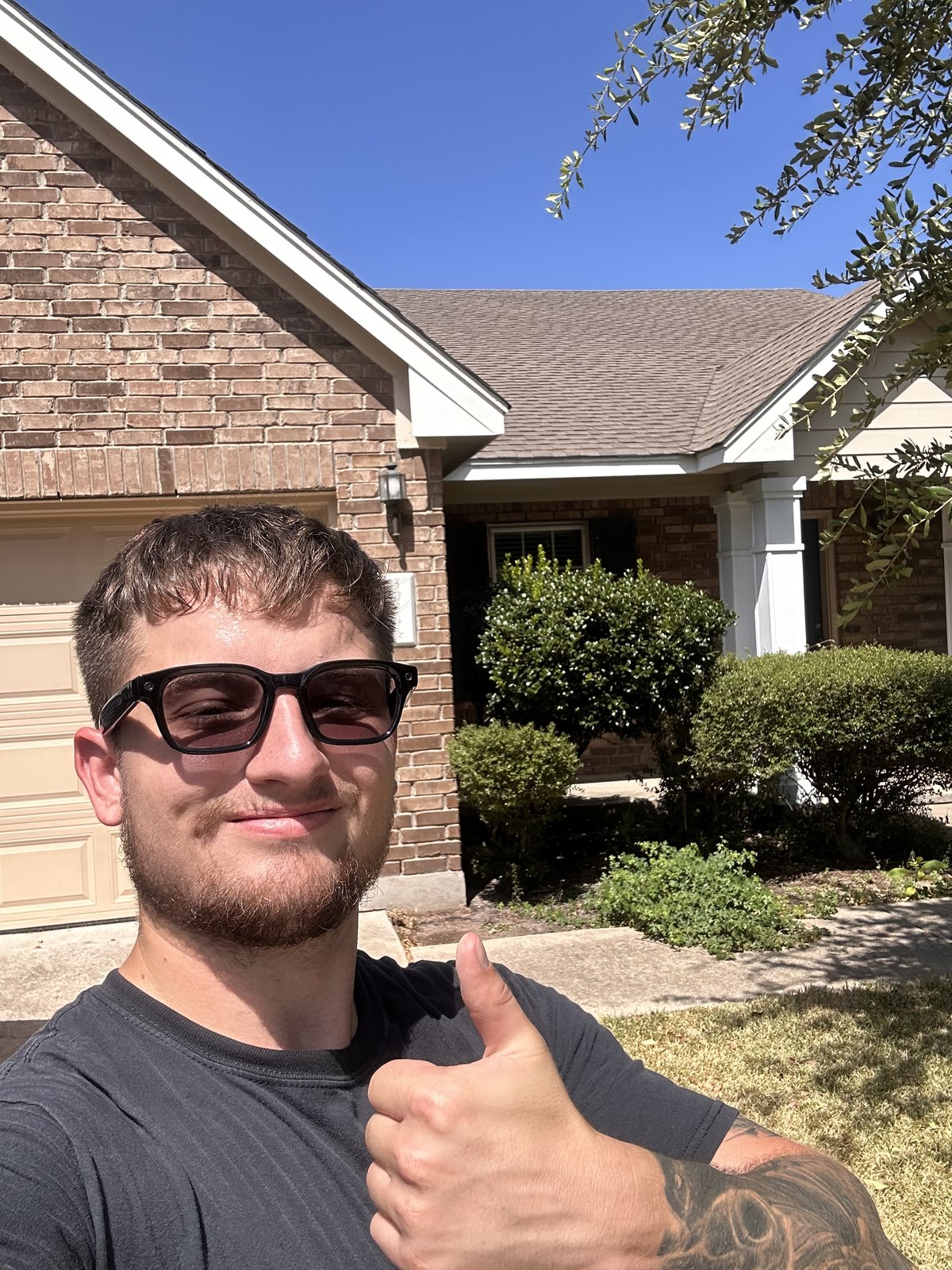 Plenox crew member on a residential driveway in front of a brick home after a roof inspection in Leander, TX