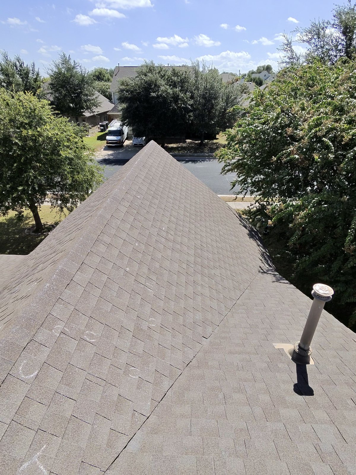 Finished hip roof with a sealed pipe boot and turbine vent under blue sky in Round Rock, TX