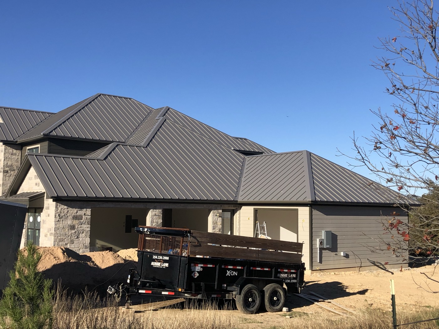 Completed dark metal roof on a stone home in Leander, TX